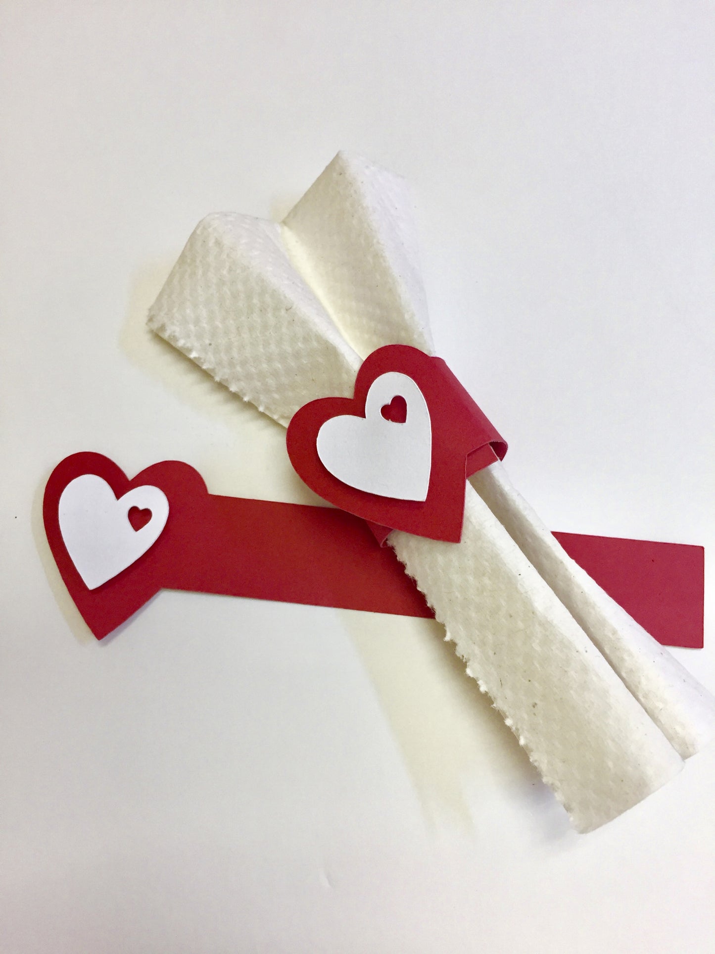 Red Heart Napkin Ring with raised white heart wrapped around a paper napkin