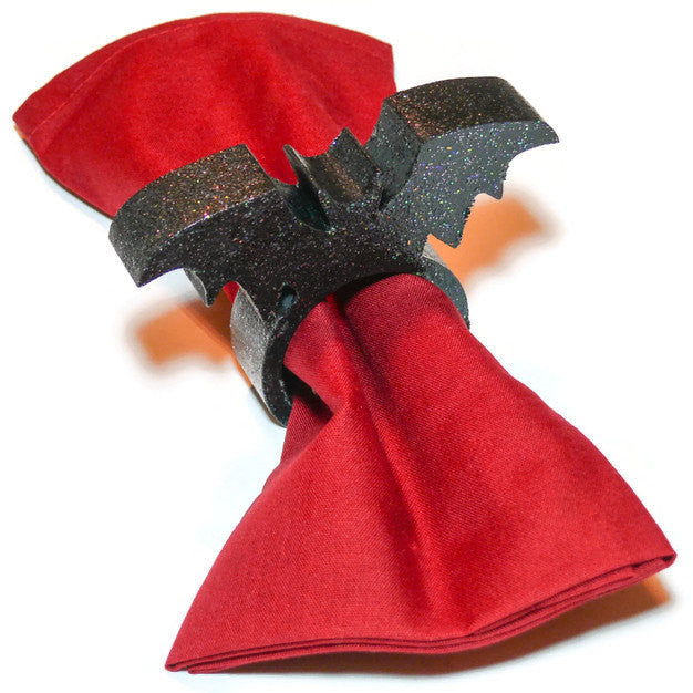 Wood Black Bat napkin Ring covered with sparkles and sealed to a gloss finish.  Displayed with a red linen napkin.